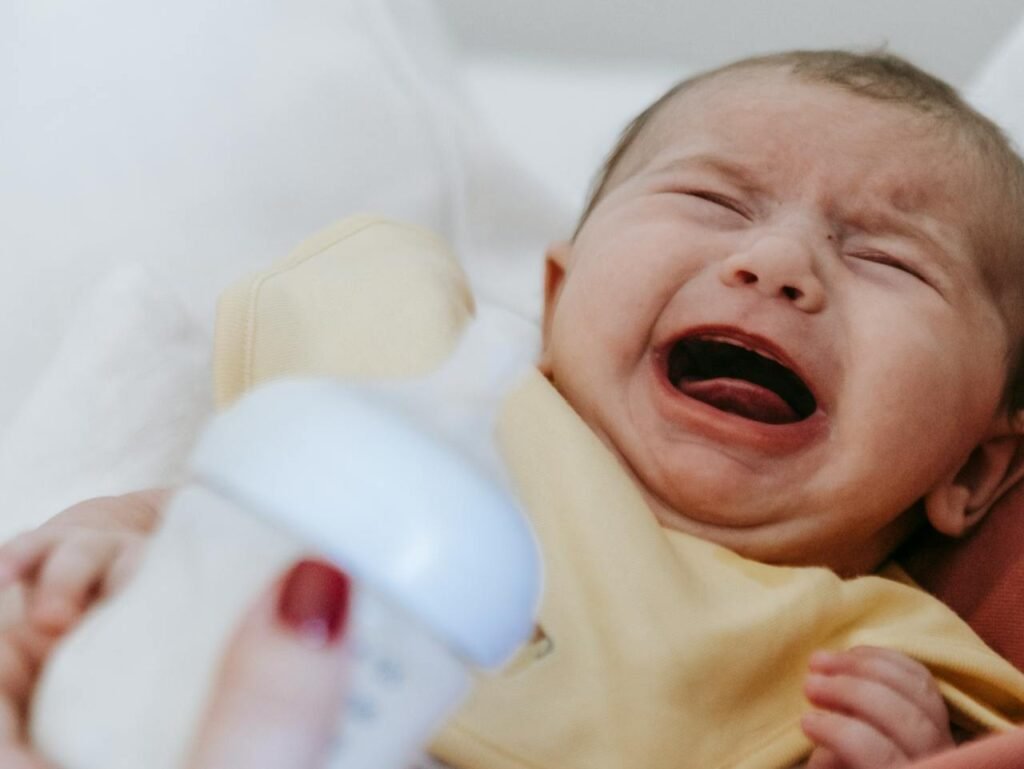 Bebis som blir matad med flaska och gråter